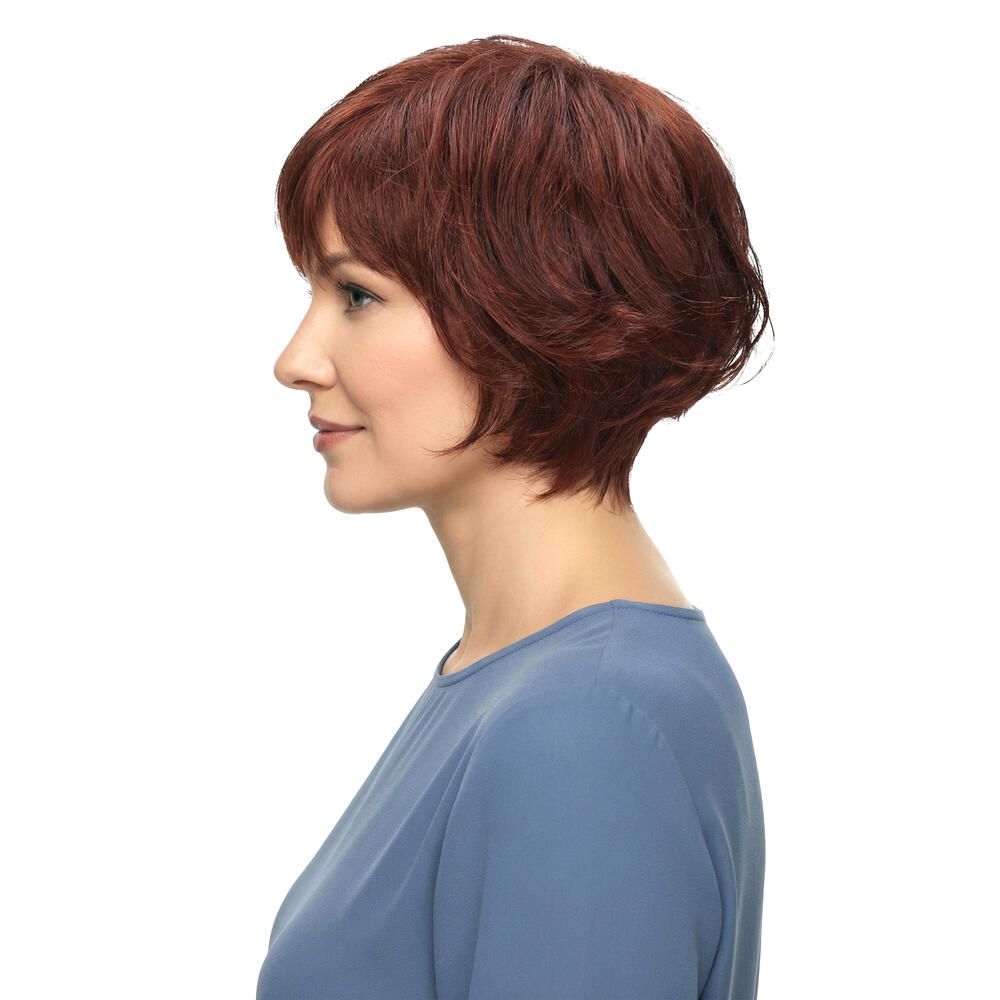 Profil einer Frau mit roter Perücke. Kurzer, gewellter Haarschnitt. Blauer Pullover. Seitenansicht.