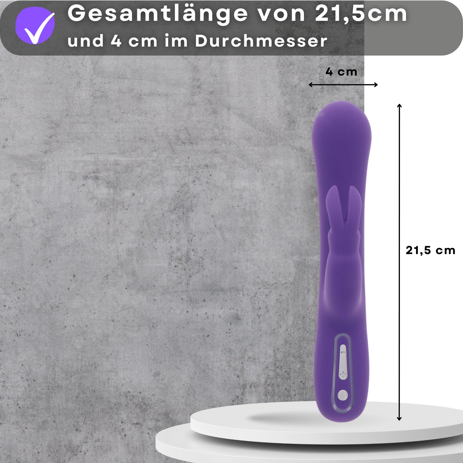 Lila Vibrator, 21,5 cm lang, 4 cm Durchmesser. Auf weißer Plattform. Hintergrund: graue Wand. Maße sichtbar.