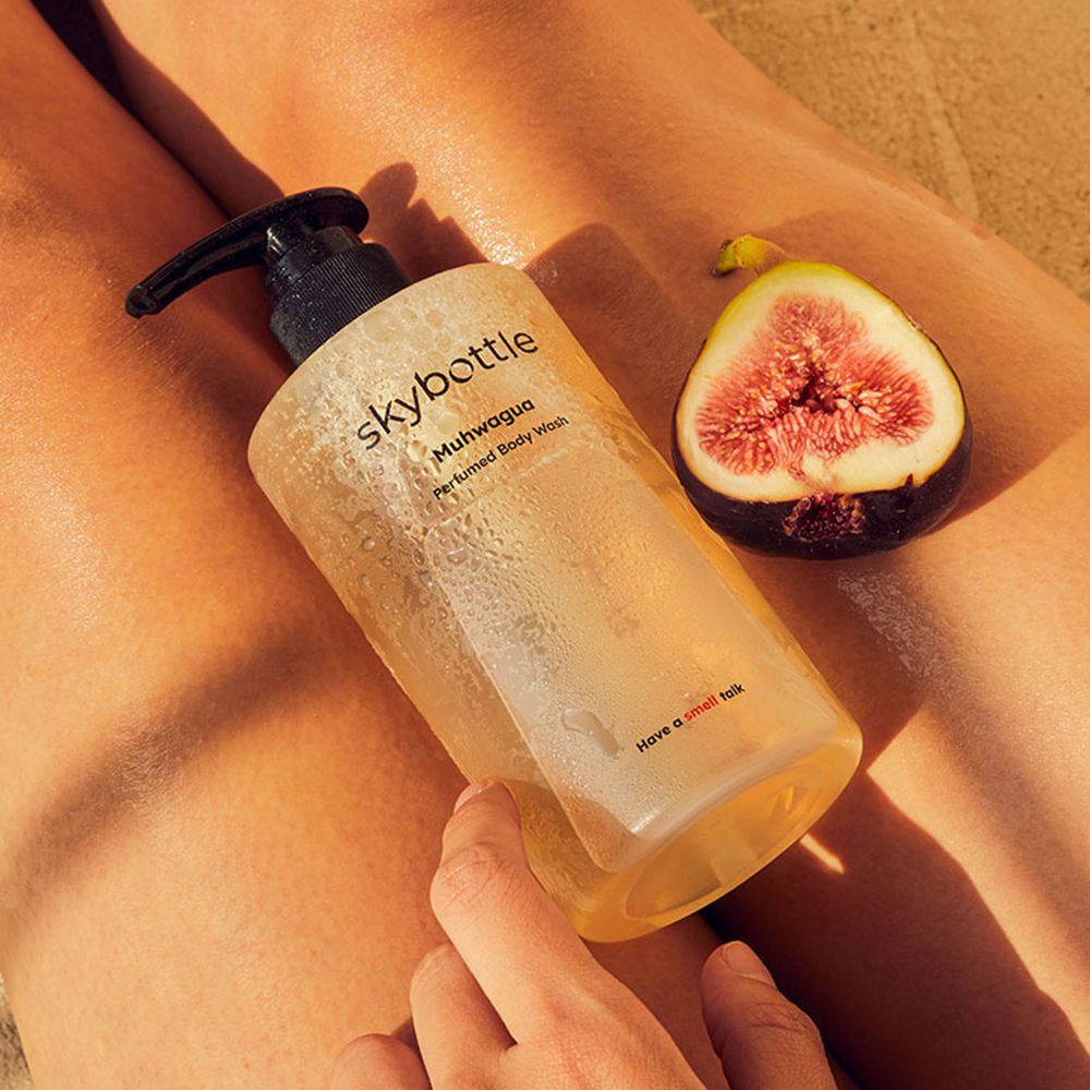 Eine Flasche SKYBOTTLE Muhwagua Duschgel und eine halbe Feige auf einem Körper. Aufschrift: Muhwagua, Perfumed Body Wash. Unter: Have a smell talk.