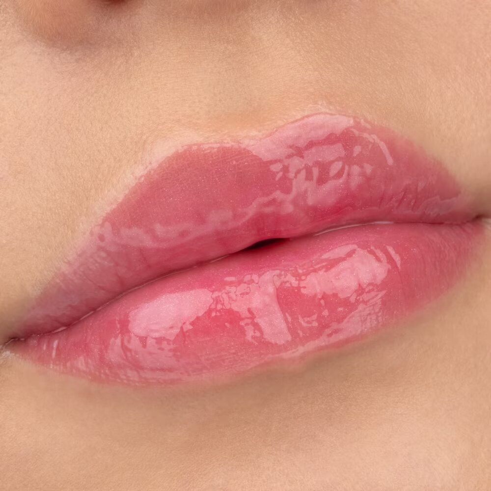 Nahaufnahme von glänzenden Lippen. Rosa Lipgloss aufgetragen.