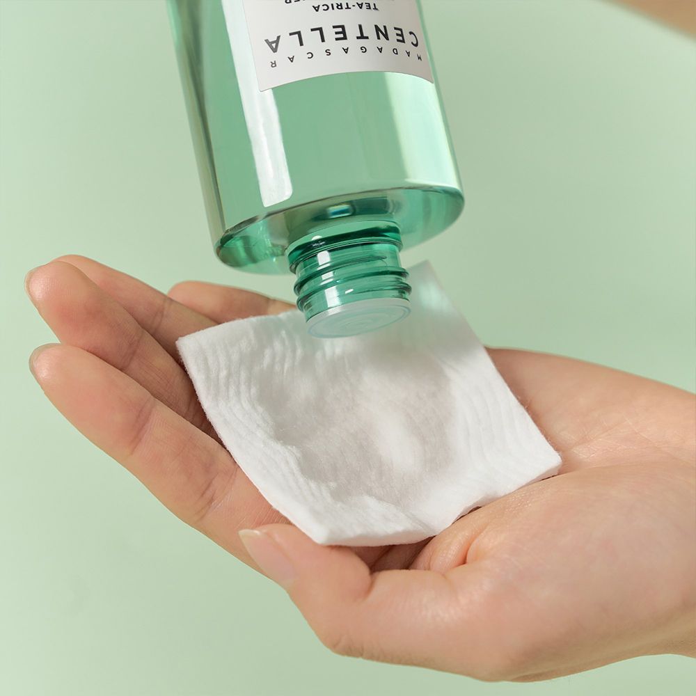 Toner wird auf ein Wattepad in einer Hand gegossen.