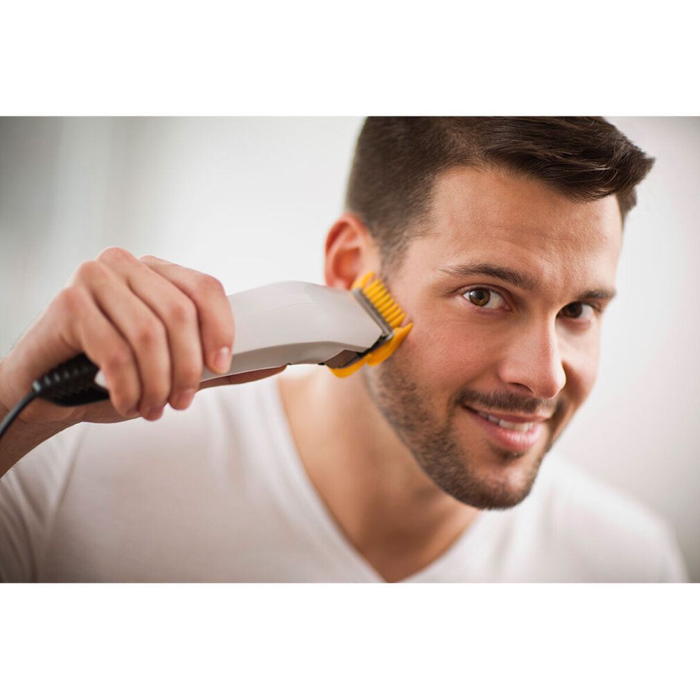 Mann rasiert sich mit einem weißen Haarschneider. Gelber Aufsatz.
