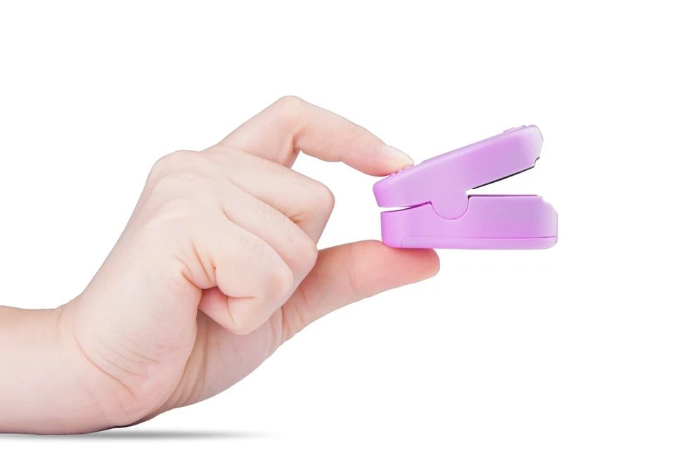 Fingerpulsoximeter in Hand gehalten. Lila Gerät, geöffnet. Zeigt die Innenseite.