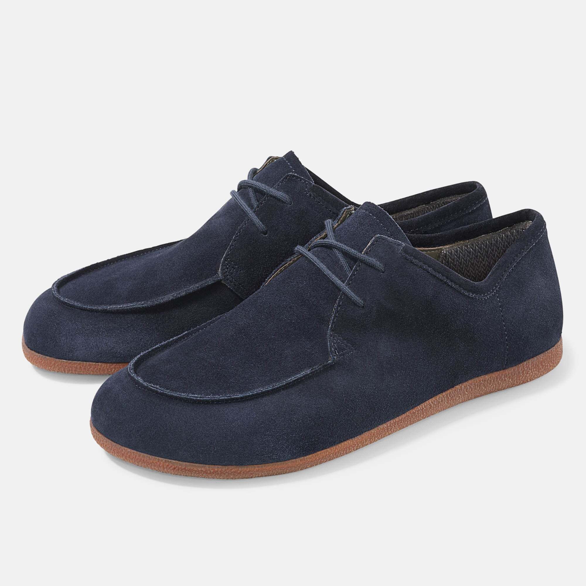 Zwei blaue Schnürschuhe aus Wildleder. Braune Sohle. Breiter Schnitt. Hellgrauer Hintergrund.