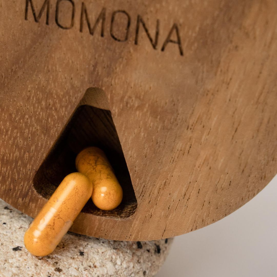 Holzdeckel mit Momona-Logo und zwei Kapseln. Kapseln liegen in einer Aussparung.