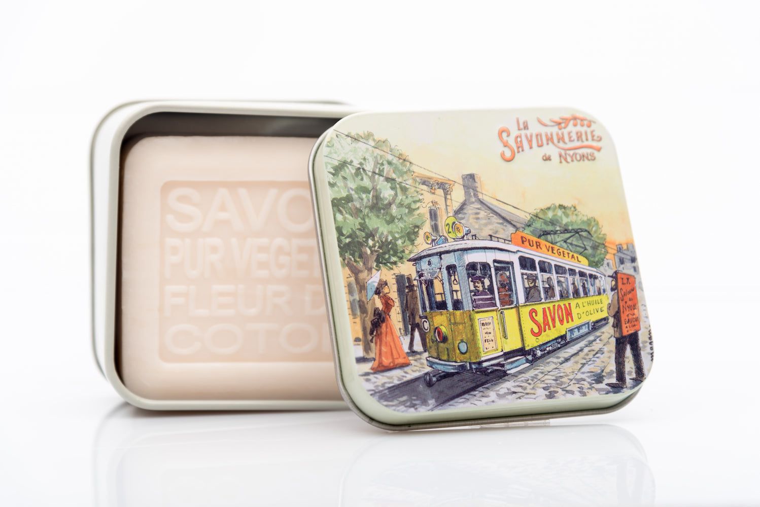 Metallbox mit Seife. Deckel mit Straßenbahn-Illustration, Schriftzug 'La Savonnerie de Nyons'. Seife mit Schriftzug 'Savon'.