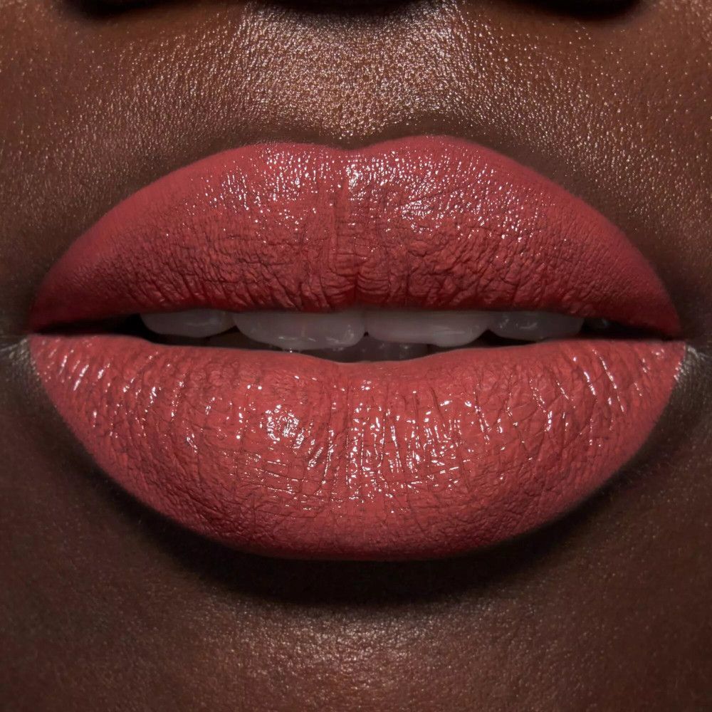 Nahaufnahme von Lippen, bedeckt mit glänzendem, braunem Lippenlack. Dunkler Hautton.