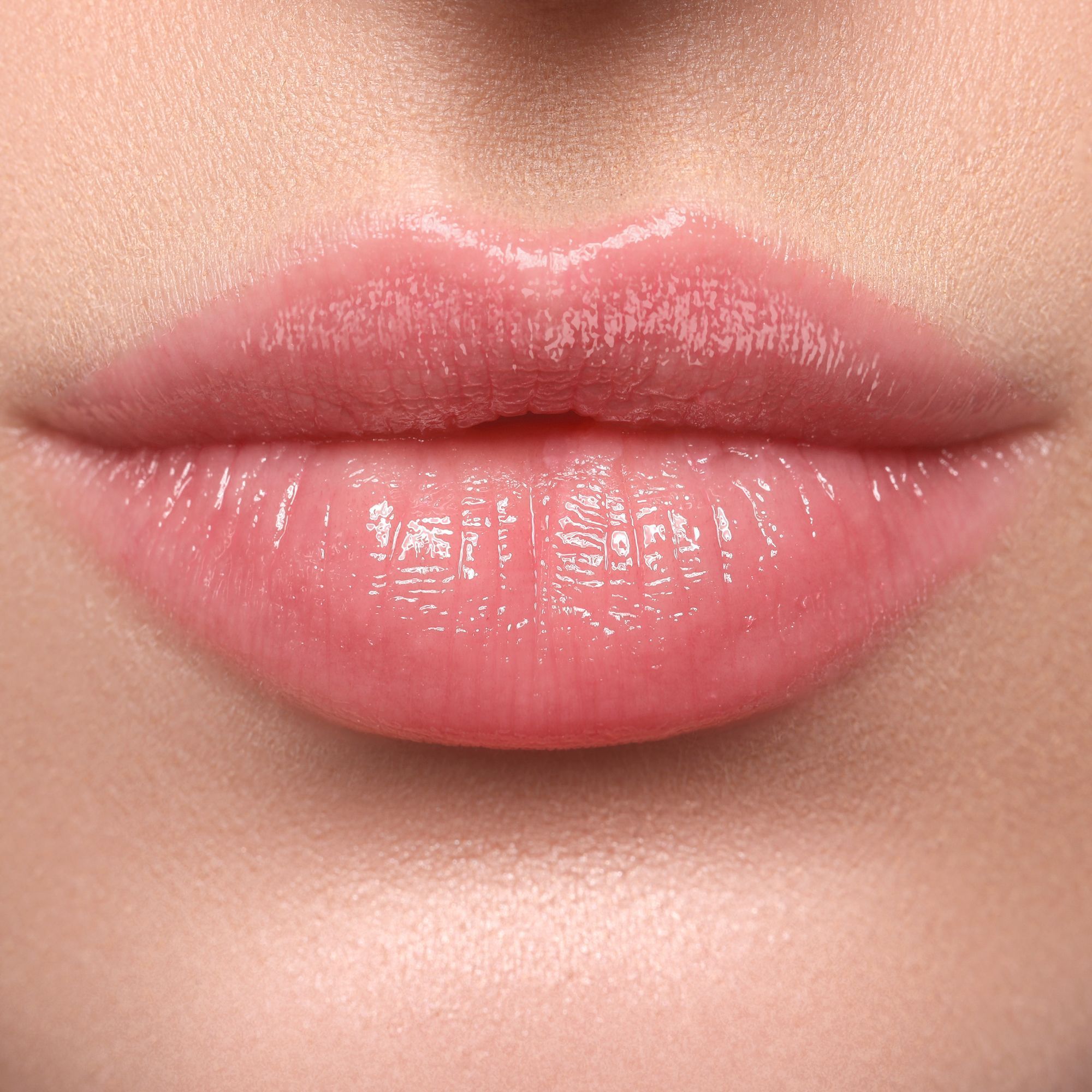 Nahaufnahme von Lippen mit glänzendem, rosa Lippenstift. Die Lippen sind leicht geöffnet.
