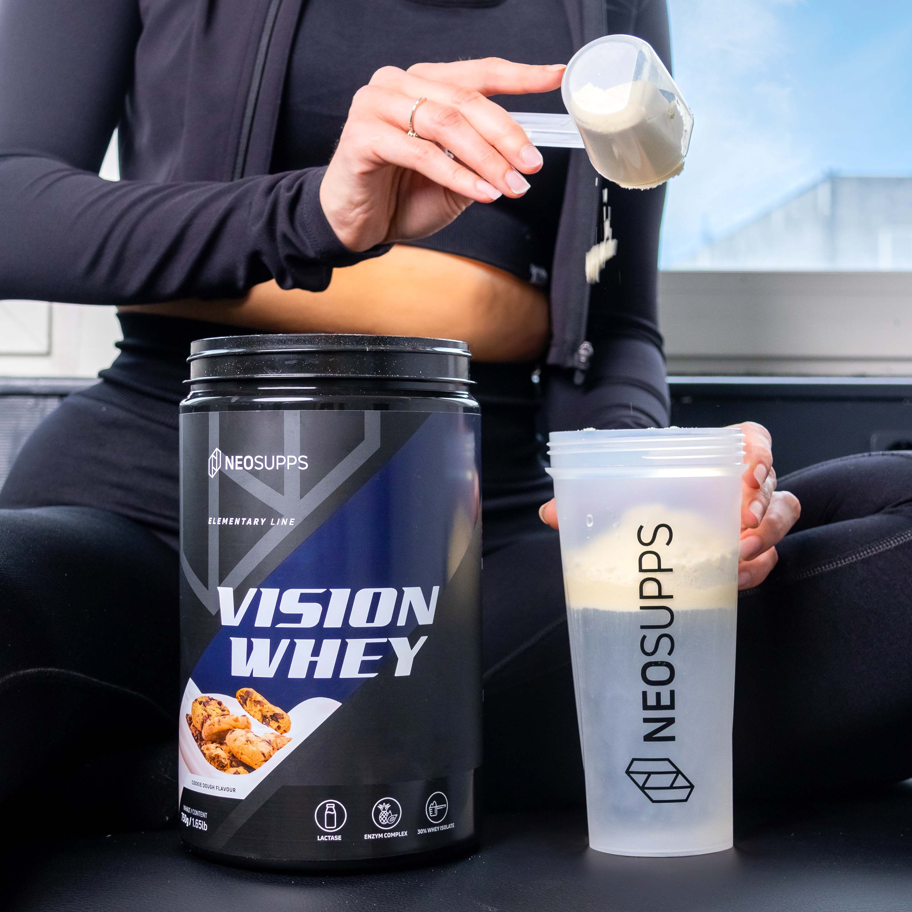 Person hält Dose "VISION WHEY" und Shaker. Logo: Neosupps. Shaker enthält Flüssigkeit. Hintergrund: Fenster mit Tageslicht.