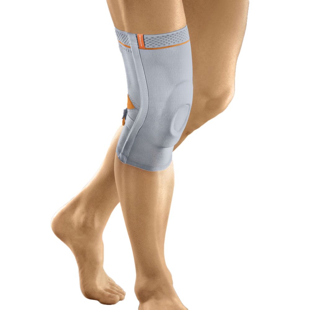 Kniebandage Sporlastic Super-Genuplus am Bein. Grau mit orangefarbenen Akzenten. Seitliche Verstärkung und Öffnung für die Kniescheibe.