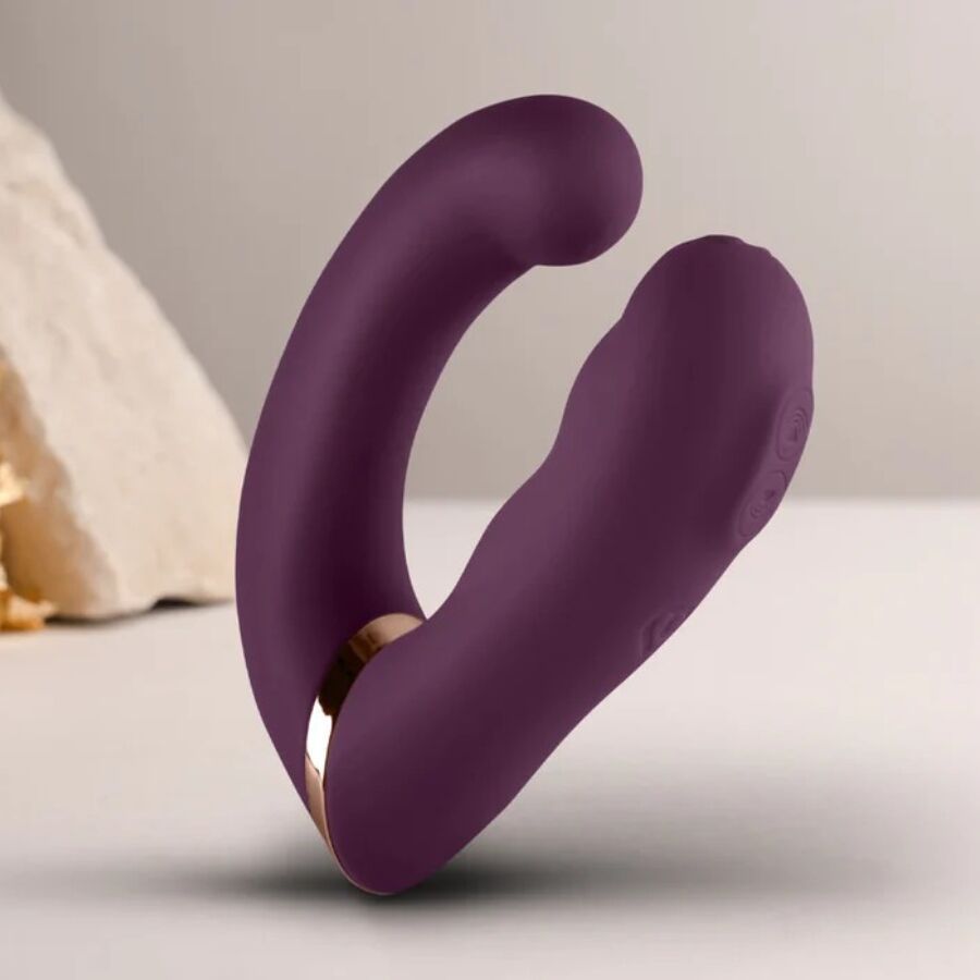 Lila Vibrator mit gebogener Form. Goldfarbener Akzent am Übergang. Auf hellem Untergrund.