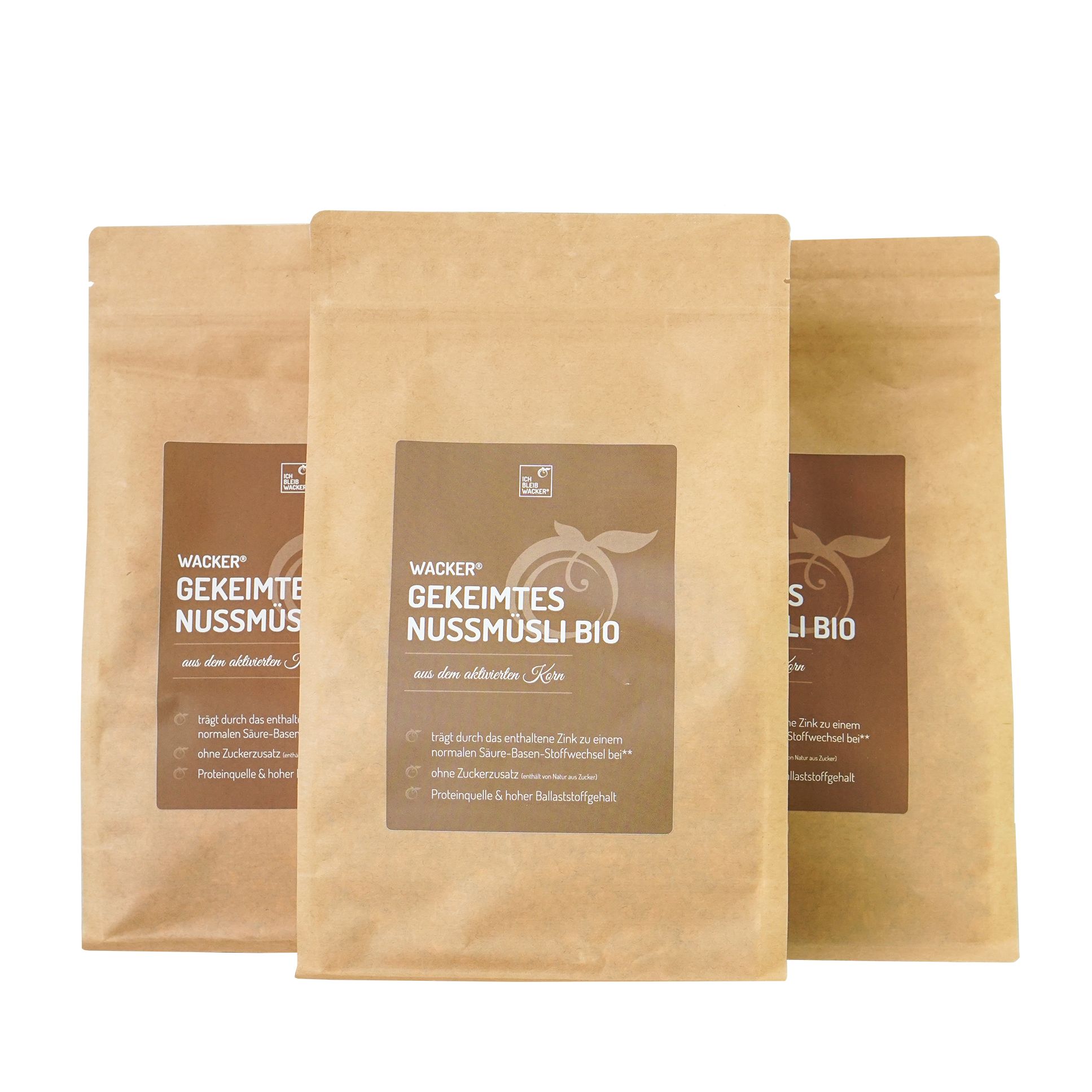 Drei Beutel Gekeimtes Nussmüsli Bio. Braune Papierverpackung mit Etikett. Aufschrift: Wacker, Gekeimtes Nussmüsli Bio.