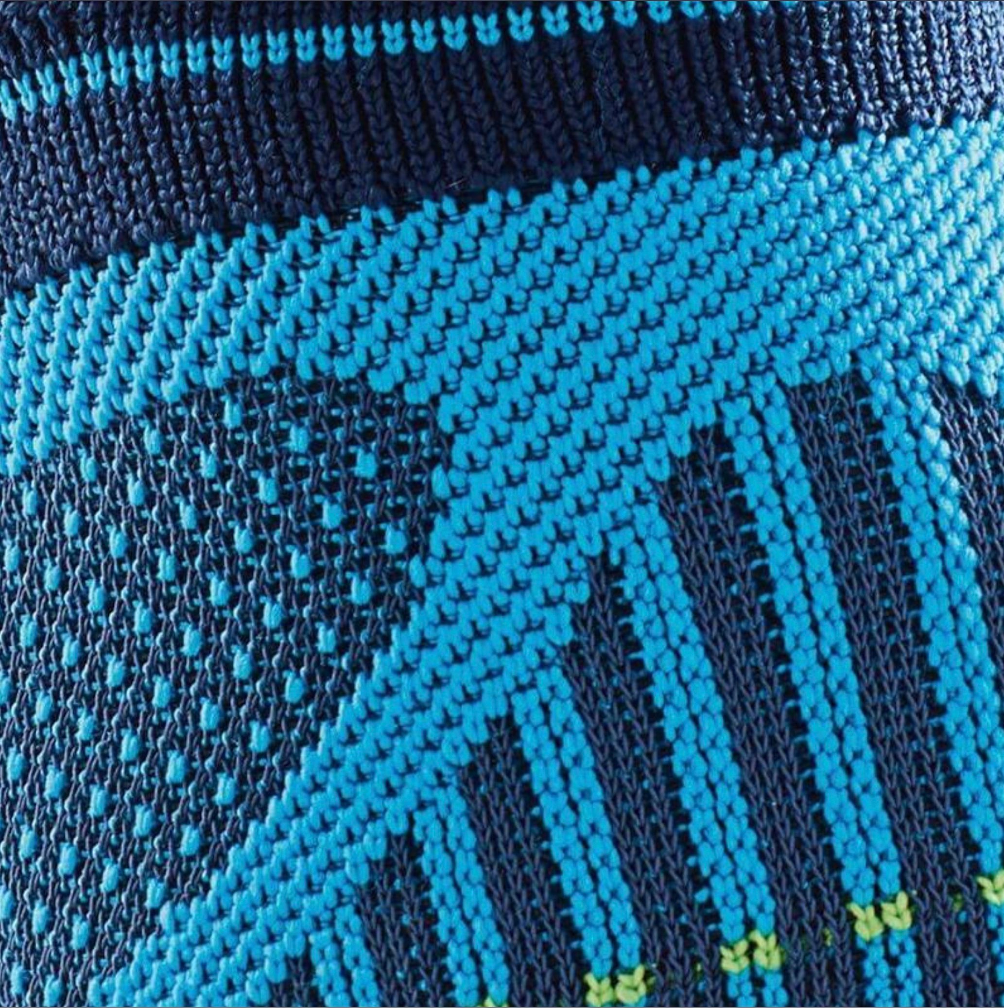Detailansicht des gestrickten Materials der Knöchelbandage. Blau-türkis Musterung.