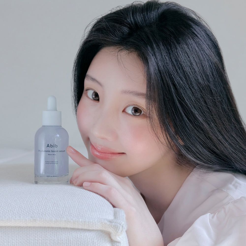 Abib Hyaluronique Serum Flasche mit Pipette, neben einer Frau mit langen schwarzen Haaren.