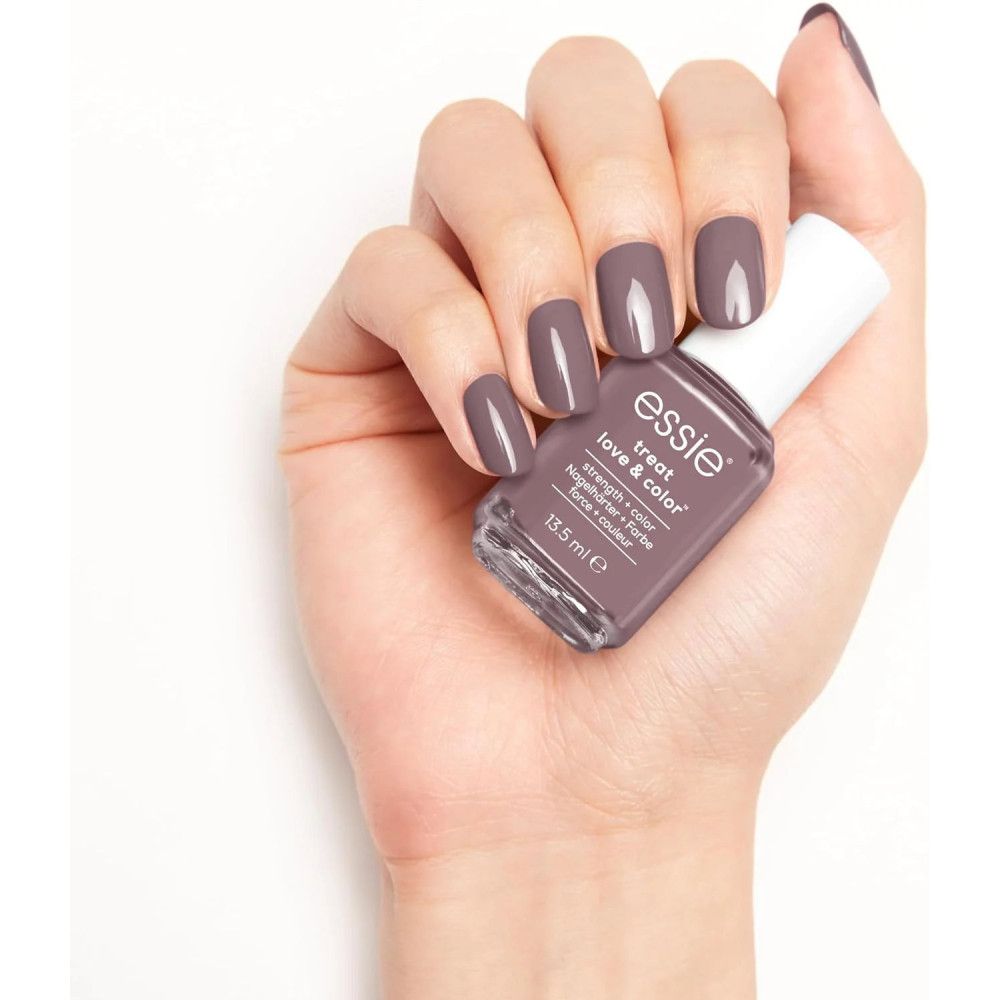 Hand mit lackierten Nägeln und Nagellackflasche. Aufschrift: Essie Treat Love & Color.
