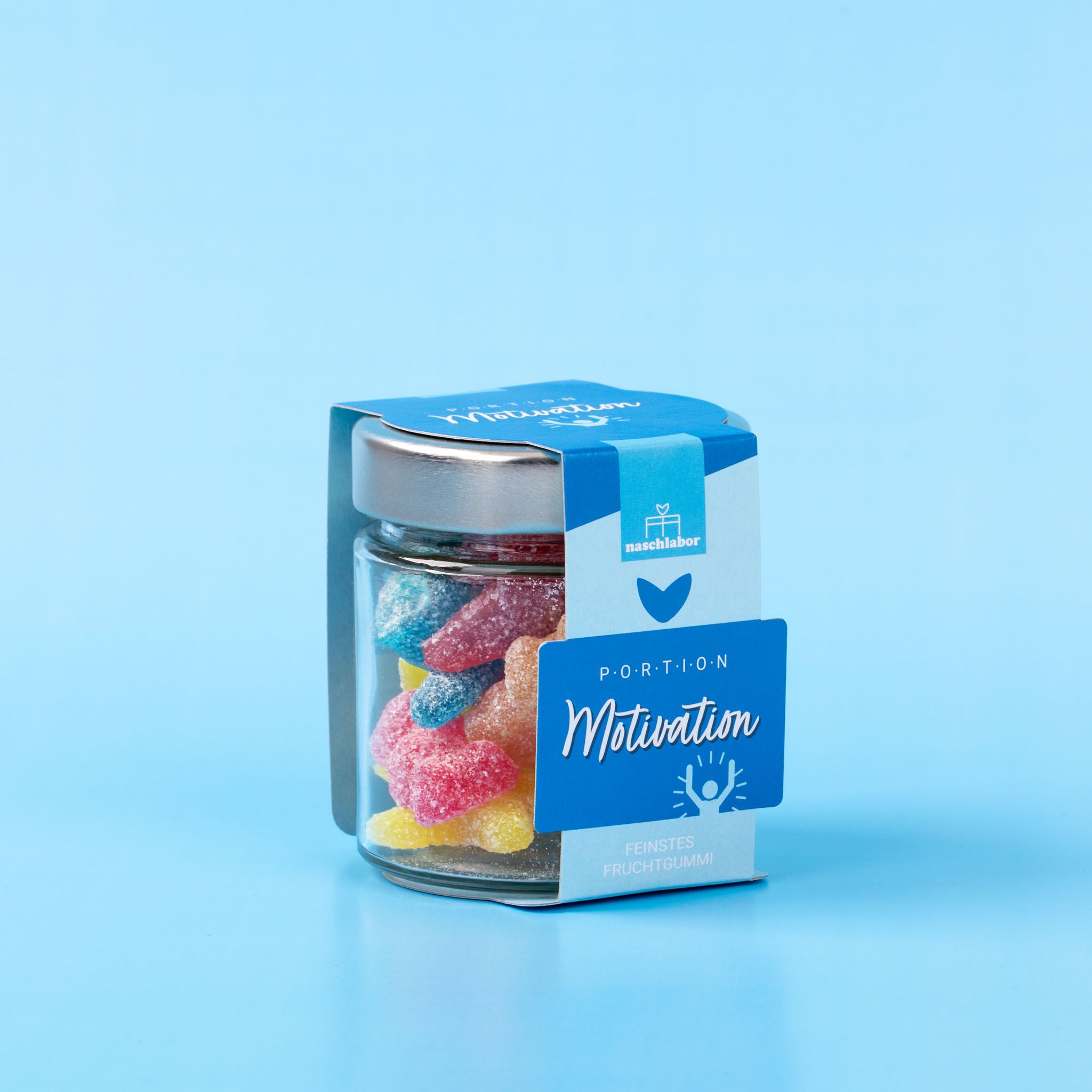Glas mit Fruchtgummi, blaue Etiketten mit 'Motivation'. Auf blauem Hintergrund.