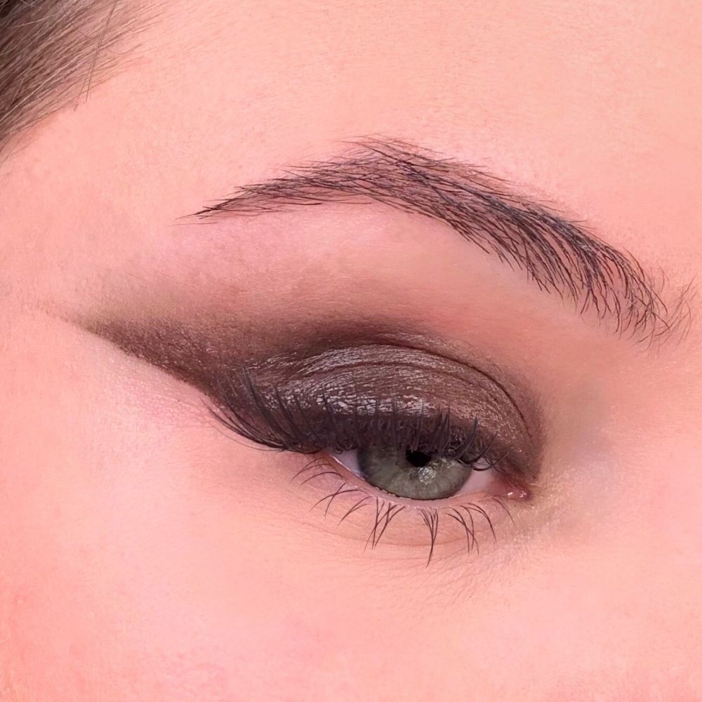 Auge mit braunem Lidschatten. Brauner Lidschatten auf dem Augenlid. Braune Wimpern. Augenbraue.