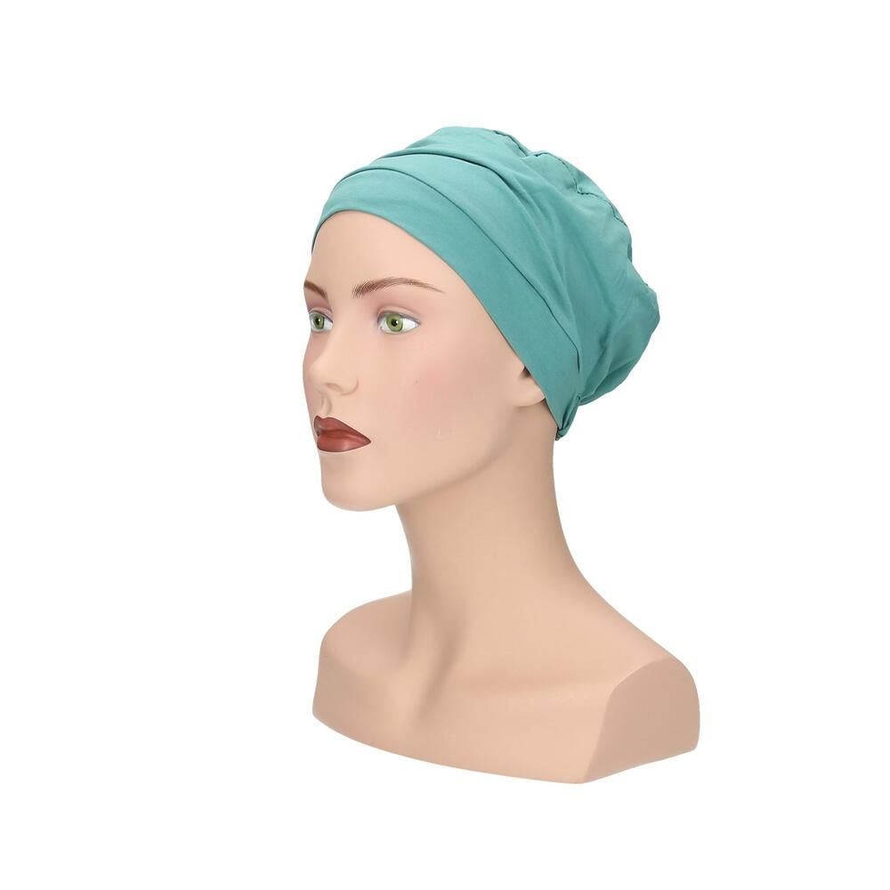 Türkisfarbener Turban auf Schaufensterpuppe. Seitenansicht. Gerüschte Details, glatter Stoff.