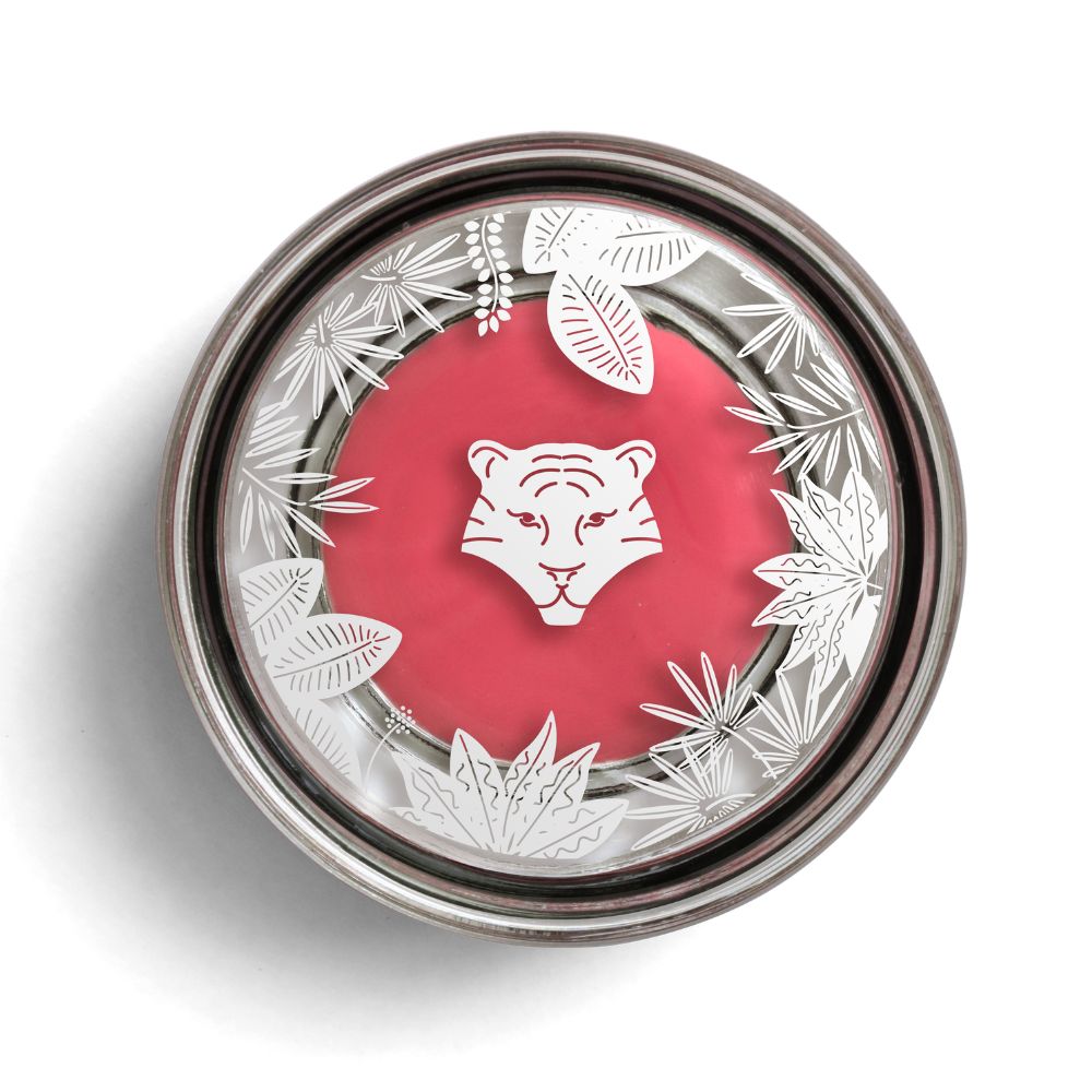 Runder Behälter mit rosa Inhalt. Deckel mit weißem Blattmuster und Tigerkopf-Logo. Metallischer Rand.