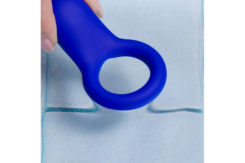 Blauer Ring aus Silikon, gehalten von einer Hand. Der Ring hat eine ovale Form mit einer Öffnung.