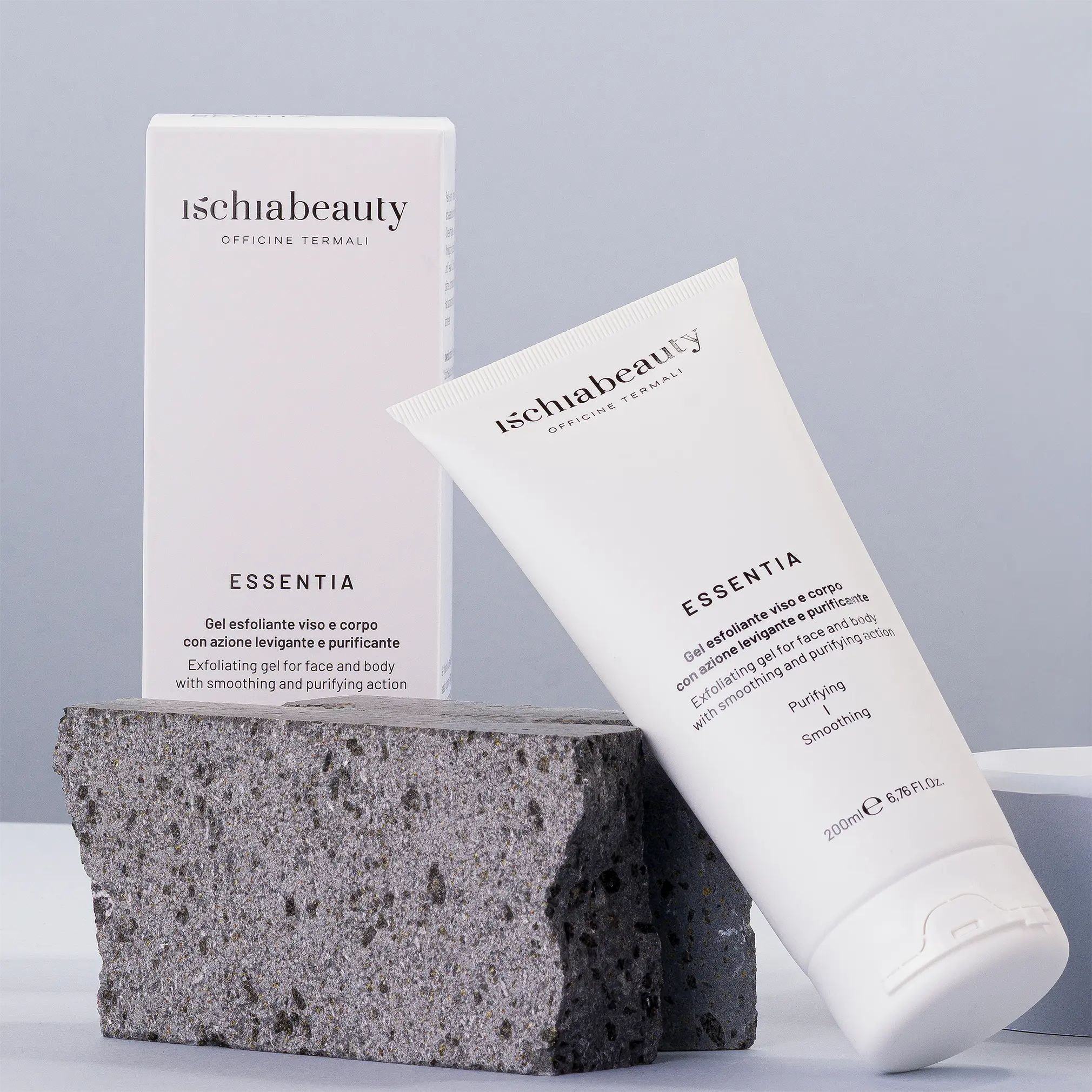 Weiße Tube und Schachtel mit Produktbeschriftung. Text: Ischiabeauty, Essentia, Gel esfoliante viso e corpo. Auf Steinblock platziert.