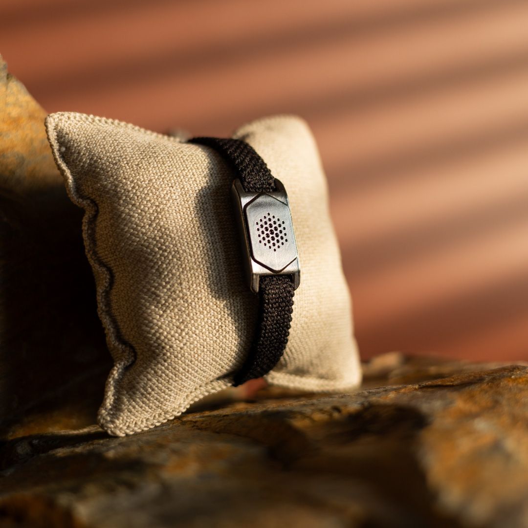 Schwarzes Armband mit metallfarbenem Element auf einem beigen Kissen. Natürlicher Hintergrund.