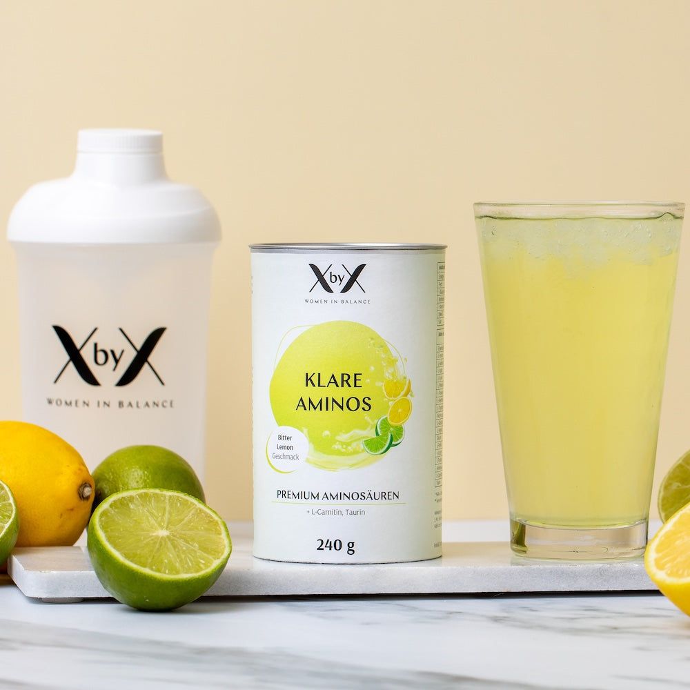 Dose und Glas mit gelbem Getränk. Daneben ein Shaker und Früchte. Auf der Dose steht "Klare Aminos".