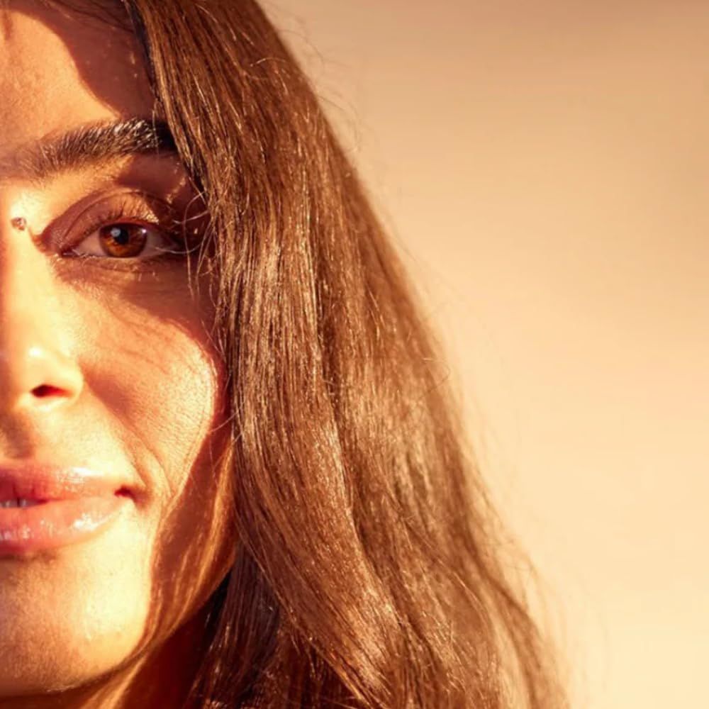 Porträt einer Frau mit braunem Haar. Sonnenlicht betont Gesichtszüge und Haarstruktur. Blick nach rechts.