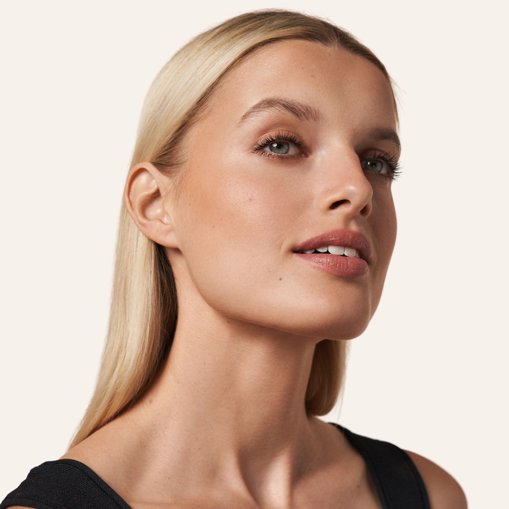 Porträt einer Frau mit konturiertem Gesicht. Blondes Haar, schwarzes Top. Natürliches Make-up.