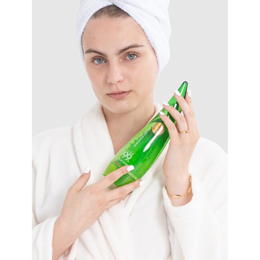 Frau mit Handtuch und Bademantel hält eine grüne Flasche Aloe 99% beruhigendes Gel.