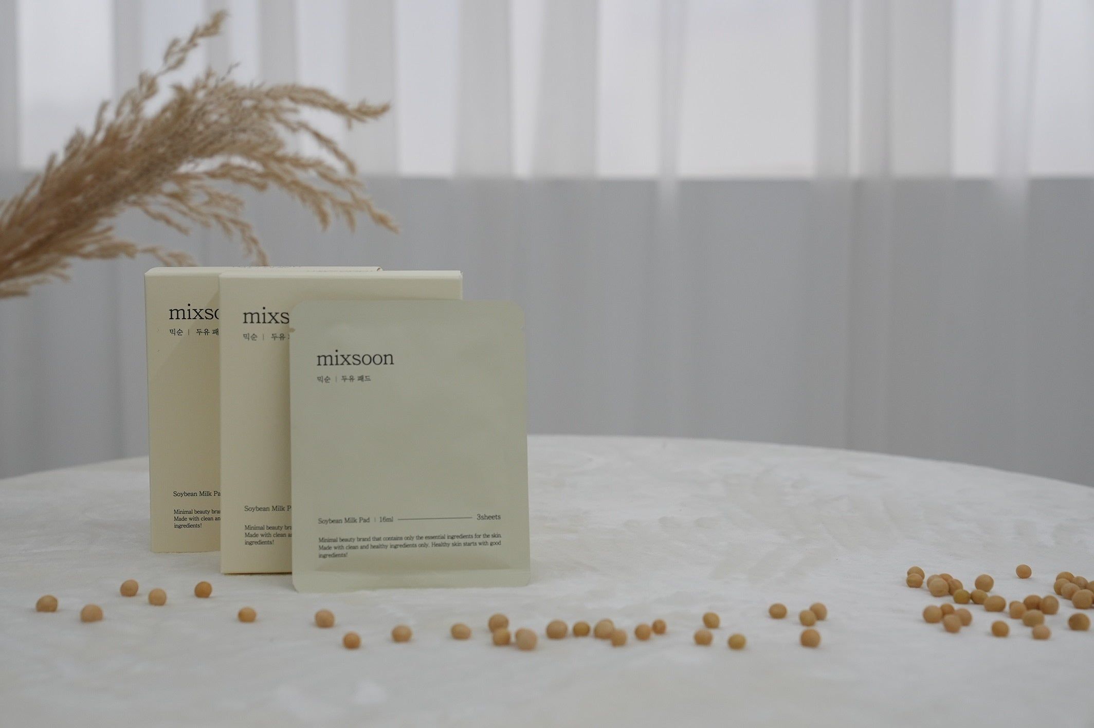 Drei Produktverpackungen und Sojabohnen auf einem Tisch. Aufschrift: mixsoon, Soybean Milk Pad.