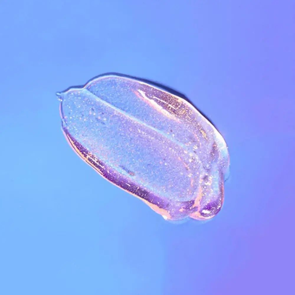 Schimmernde, gelartige Substanz auf blauem Hintergrund. Farbverlauf von violett nach blau. Glitzerpartikel sichtbar.