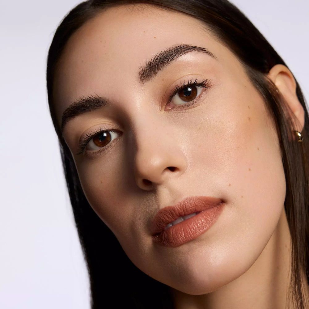 Porträt einer Frau mit Lippenstift. Die Lippen sind mit einem braunen Farbton geschminkt. Deutliche Textur und Farbe.