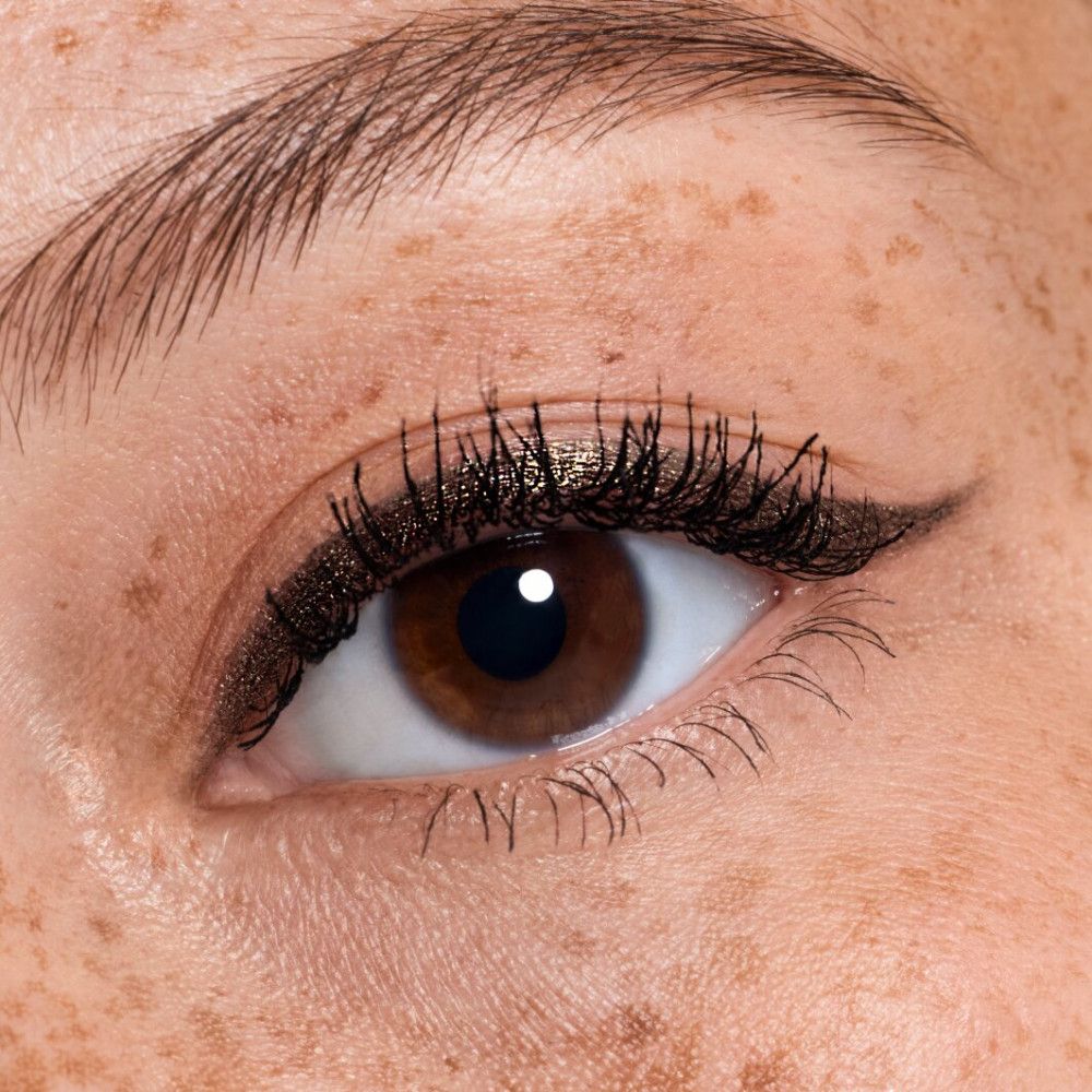 Nahaufnahme eines Auges mit aufgetragenem Augen-Make-up. Sommersprossen sind sichtbar.