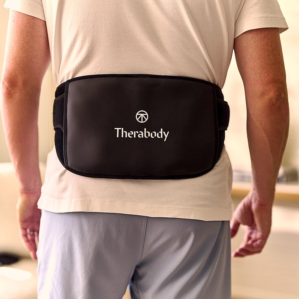 Mann trägt einen schwarzen Therabody Massagegurt. Therabody-Logo sichtbar. Rückansicht.
