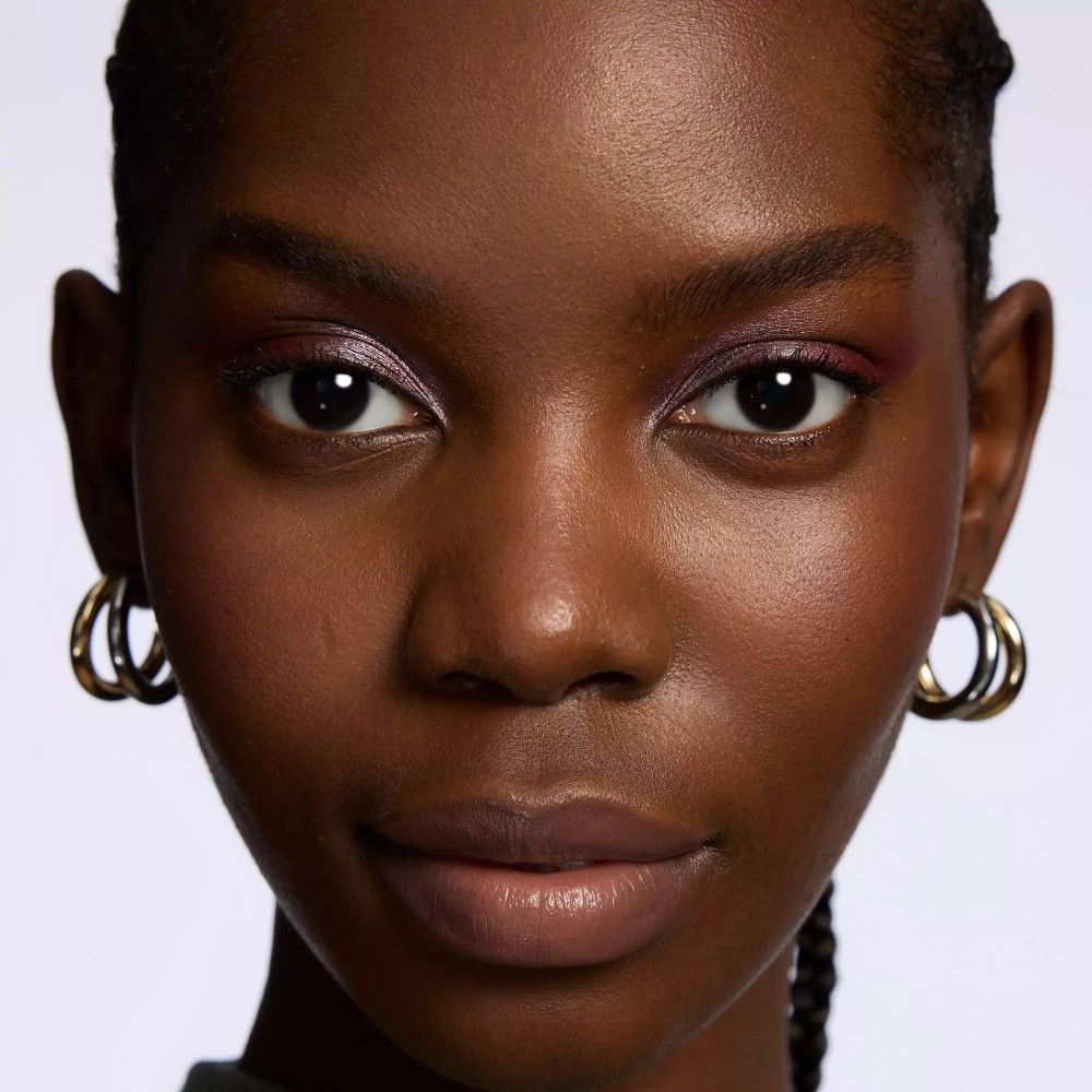 Nahaufnahme eines Gesichts mit Lidschatten. Goldene Ohrringe.