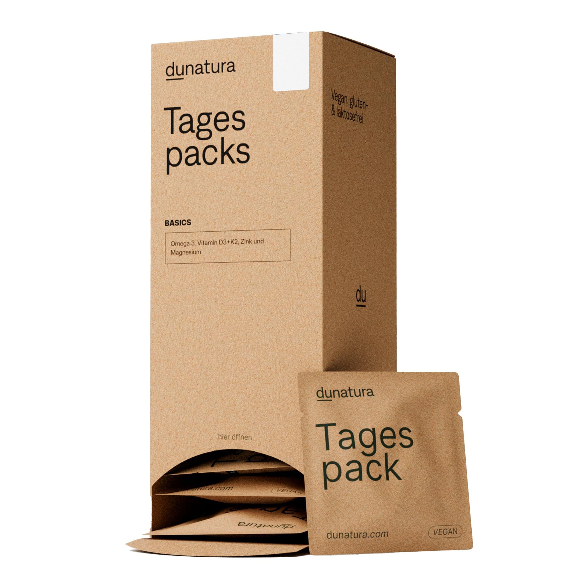 Kartonverpackung mit "Tagespacks"-Aufdruck. Einzelne Beutel liegen daneben. Aufdrucke: "Vegan", "dunatura.com".