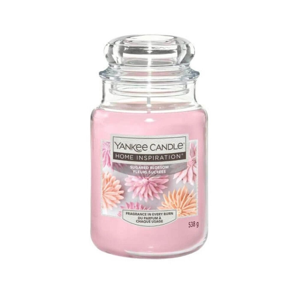 Duftkerze im Glas mit Deckel. Rosa Wachs, Etikett mit floralem Design und Text. Marke: Yankee Candle Home Inspiration.