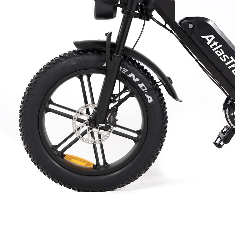 Nahaufnahme des Vorderrads eines schwarzen E-Bikes mit Kenda-Reifen. Gelber Reflektor.