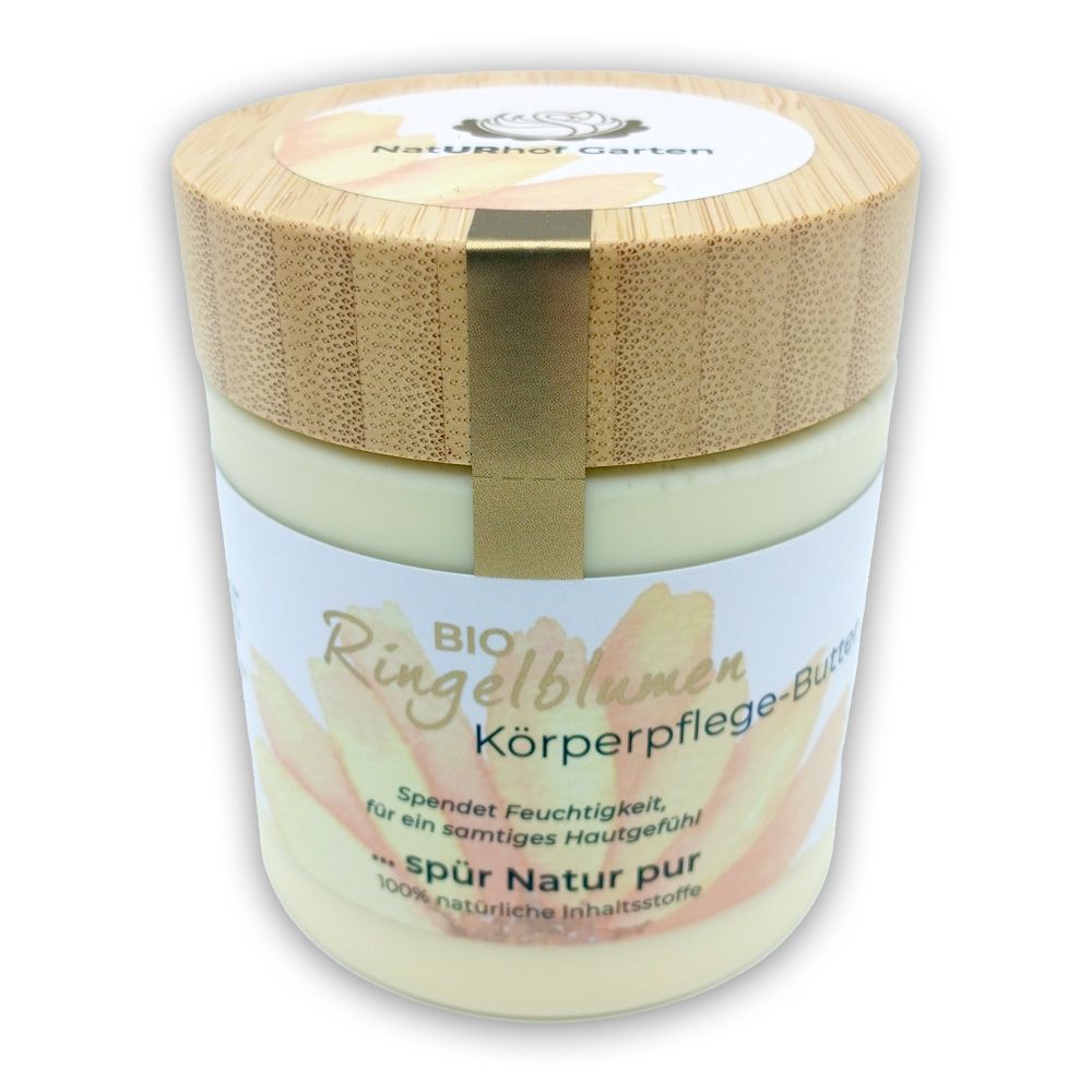 Cremebehälter mit Holzdeckel. Aufschrift: Ringelblumen Körperpflege-Butter. Bio-Zertifizierung. Gelbliche Creme. Etikett mit Blütenmotiv.