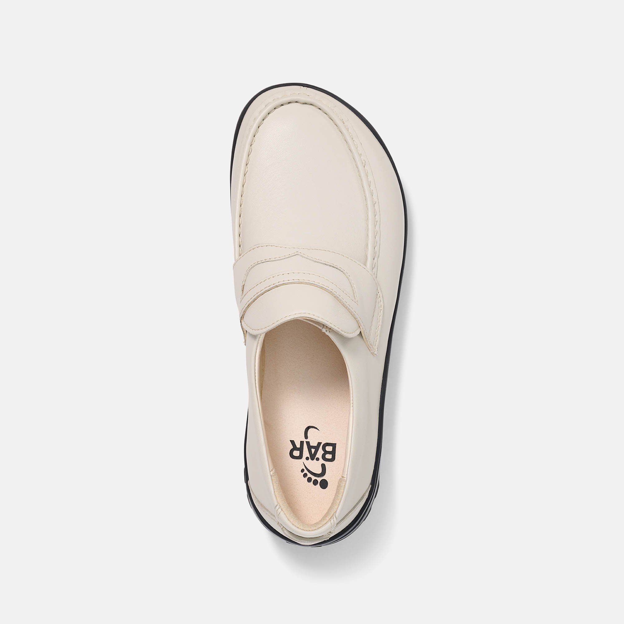 Draufsicht auf einen cremefarbenen Slipper mit schwarzer Sohle. Logo auf der Innensohle. Breiter Schnitt.