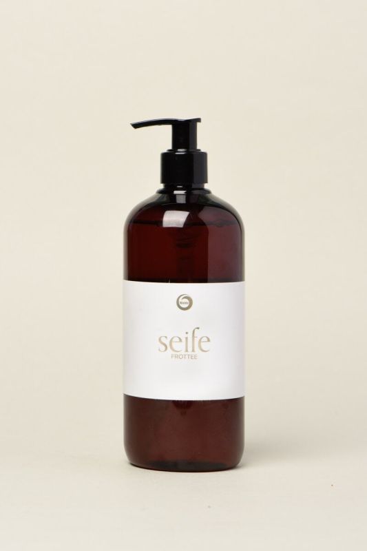 Braune Flüssigseifenflasche mit schwarzem Spender. Auf weißem Etikett steht "seife frottee".
