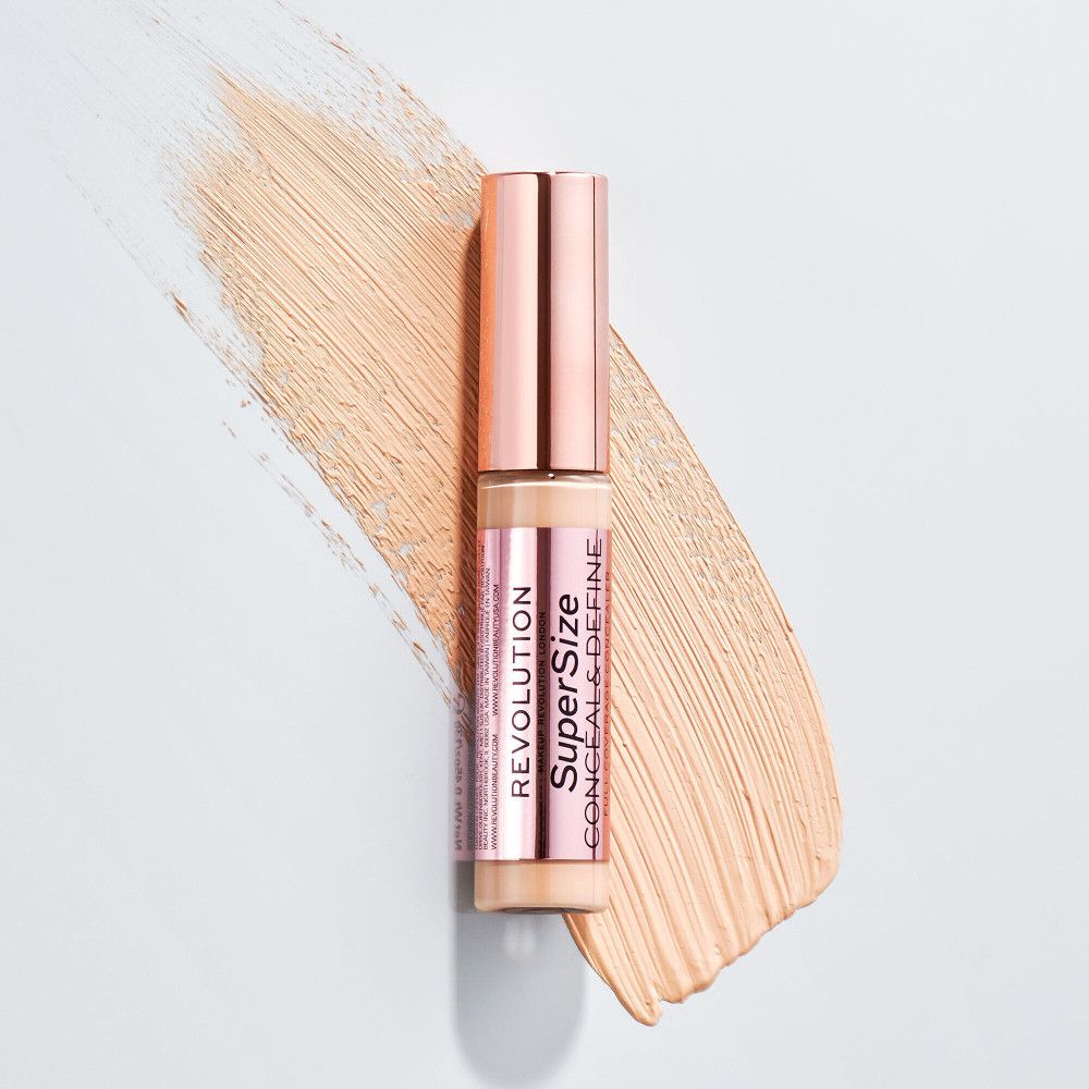 Concealer-Tube mit roségoldfarbenem Deckel. Aufschrift: Super Size Conceal & Define. Helle, cremefarbene Textur auf Abstrich.