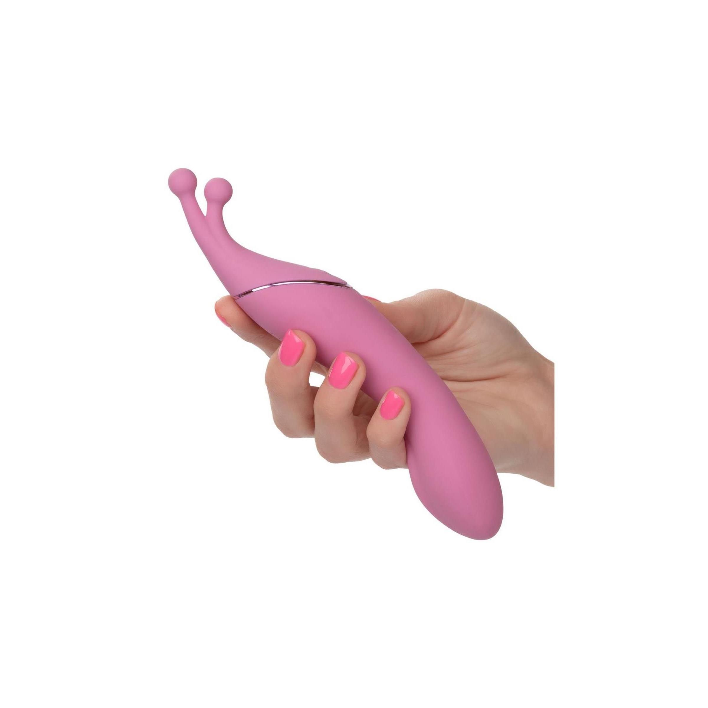 Rosa Massagegerät in einer Hand gehalten. Zwei Spitzen. Silberfarbene Akzente. Glatte Oberfläche.