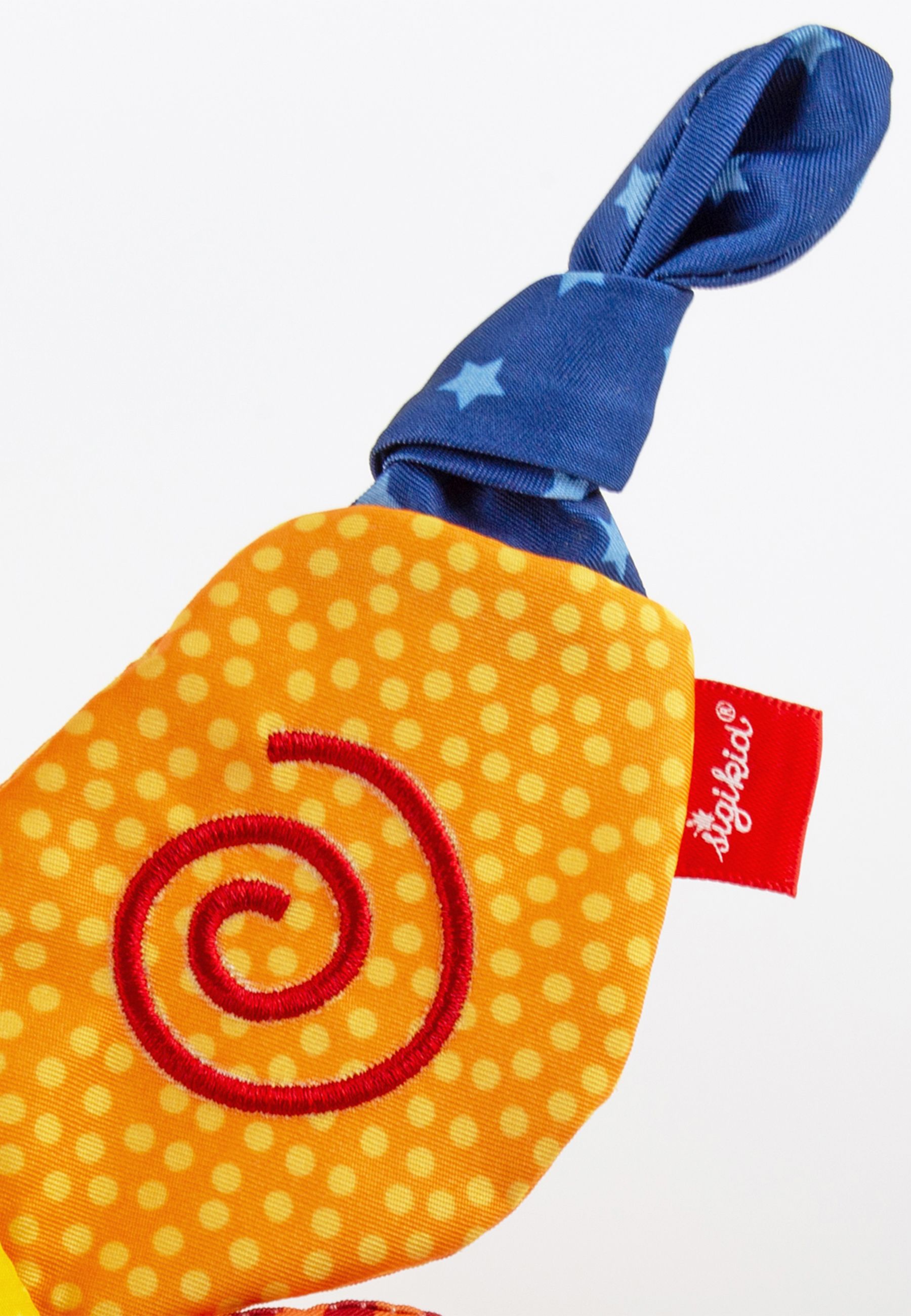 Detail eines Schmetterlingsflügels. Orangefarbene Punkte, rotes Spiralmuster. Blaues Sternenmuster. Rotes Label mit Logo.