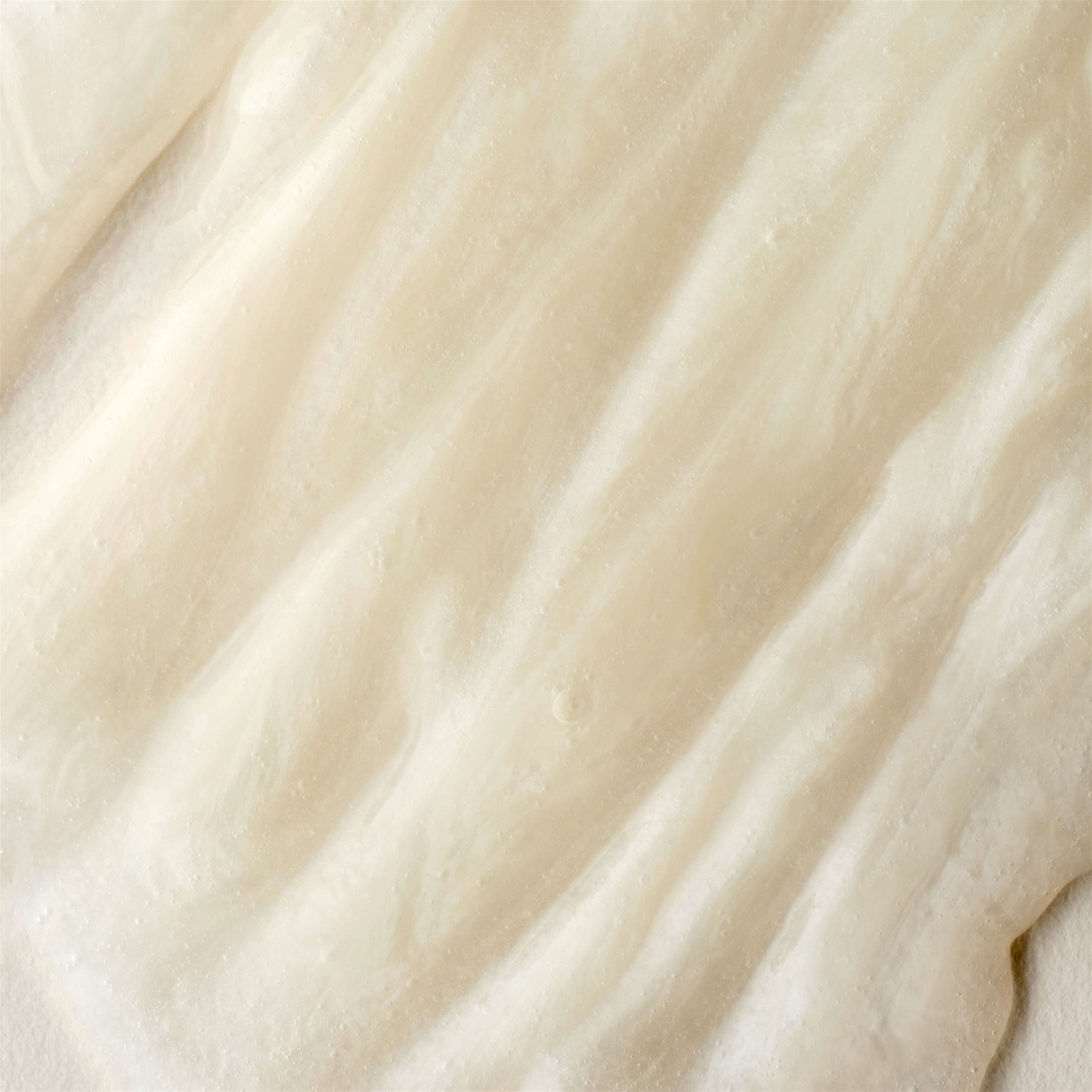 Nahaufnahme einer cremefarbenen, glatten Substanz. Textur mit wellenförmigen Linien.