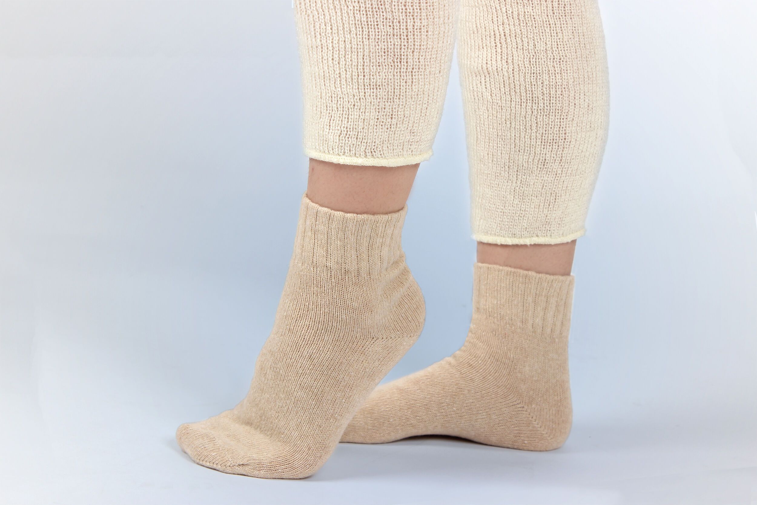 Beige Kuschelsocken, Beinlinge. Merino und Kaschmir. Nahaufnahme. Auf hellem Hintergrund.
