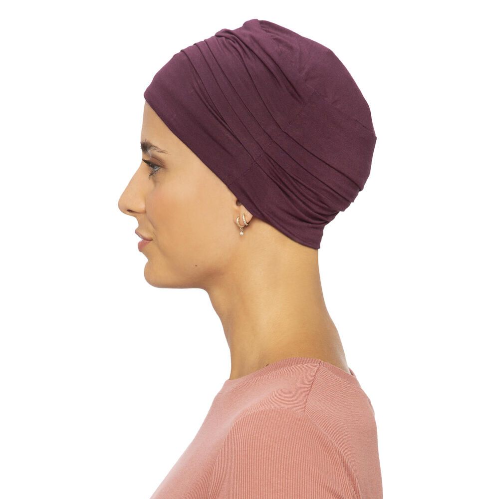 Burgunderfarbener Turban. Seitenansicht. Gerüschte Textur. Angenehmes Material. Auf hellem Hintergrund. Frau mit Ohrringen.