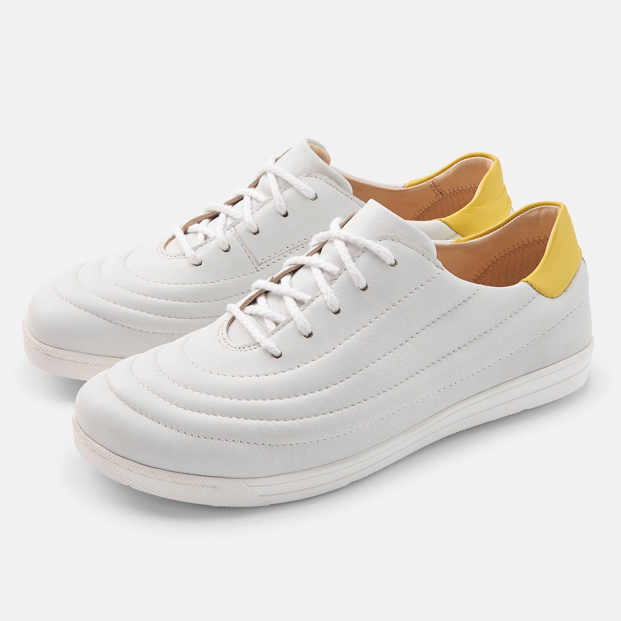 Zwei weiße Schnürschuhe mit gelben Fersenkappen. Gepolstertes Design. Flache Sohle.