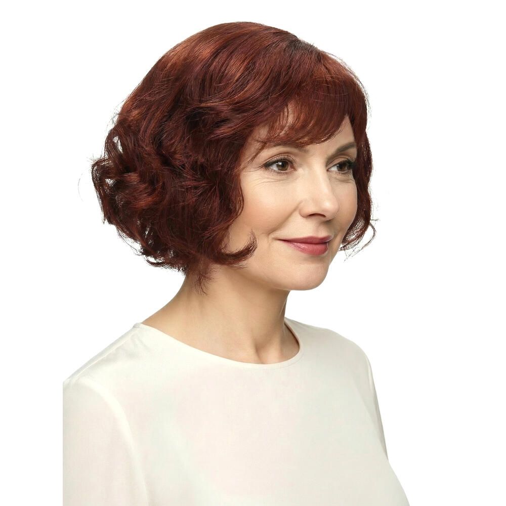 Frau mit rotbrauner, gewellter Perücke. Blick zur Seite, vor weißem Hintergrund.